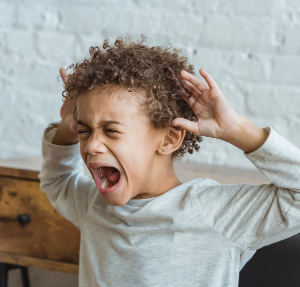 A little boy screaming with his hands on his head, illustrating that Susan Gonzales helps children manage frustration.