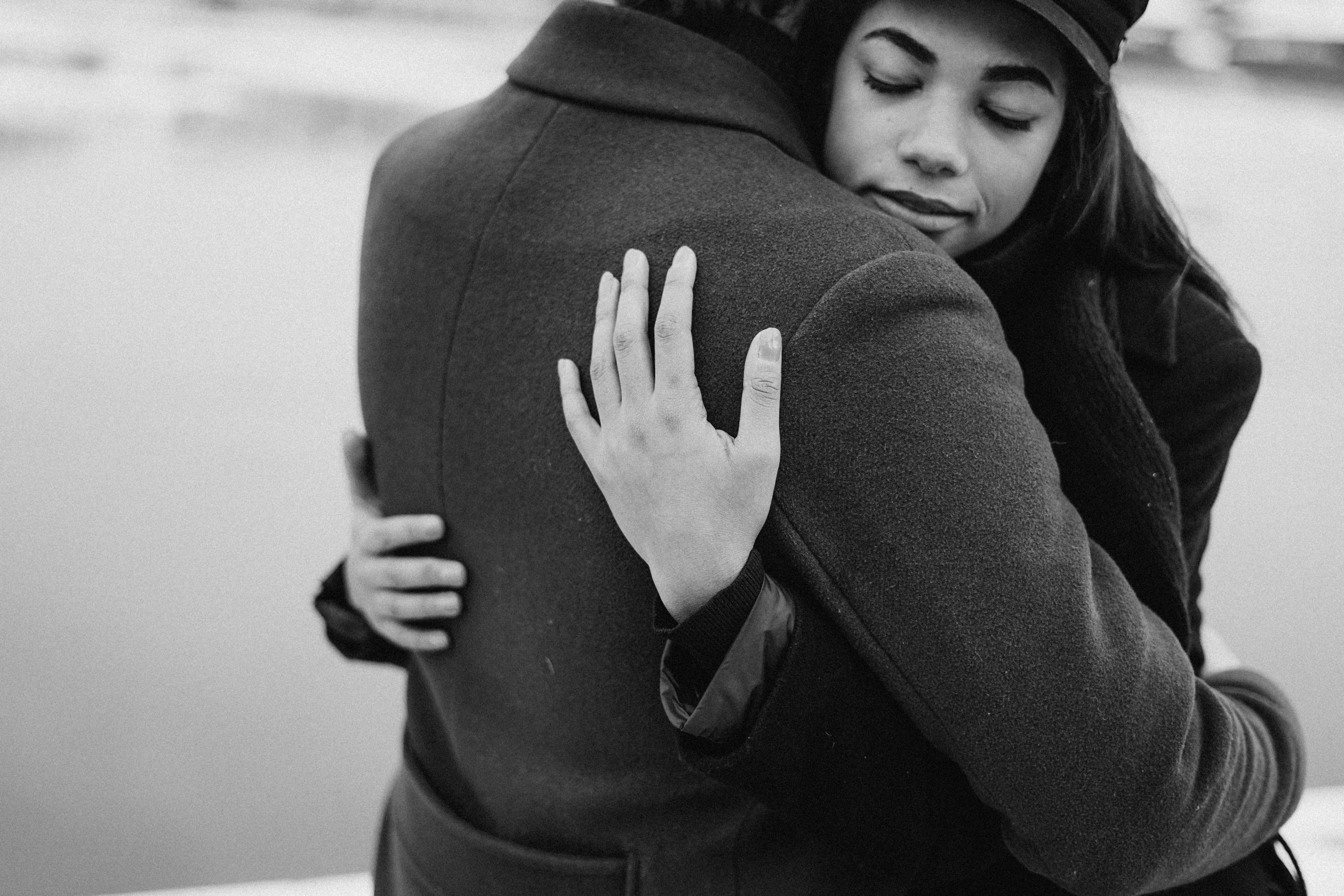 Woman hugging partner- greyscale photograph.