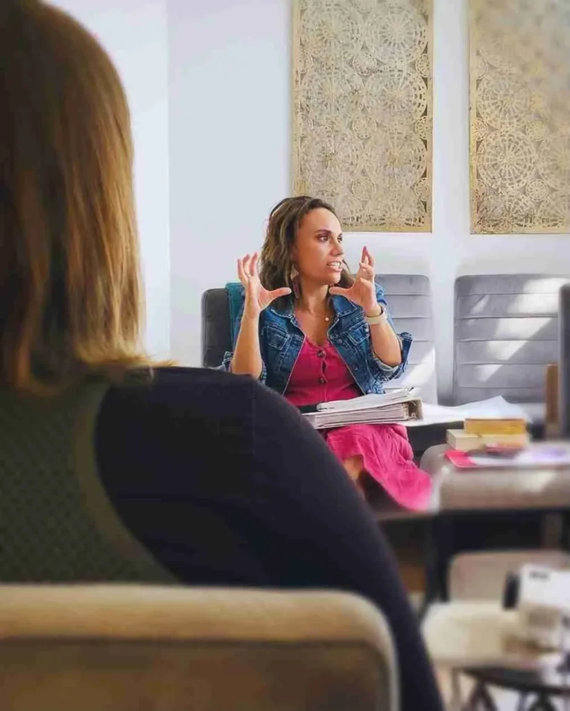 Two women talking and writing in notebooks, illustrating that Susan Gonzales provides clinical supervision and training.